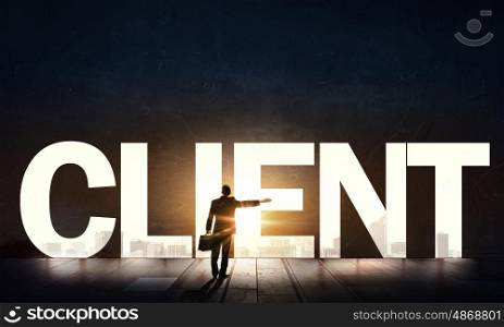 Client solicitation concept. Back view of businessman standing in light of word client