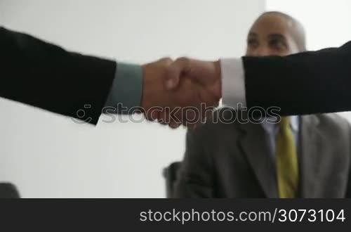 Clients meeting with consultant in corporate office. The team of business people shakes their hands and sit down talking. Closeup shot