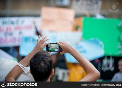Climate Change Protest on the Street. Focus on Man Holding Phone and Recording Protest.. Climate Change Protest.
