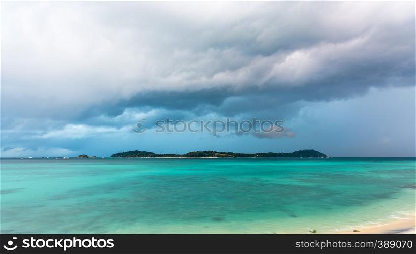 Climate change with storm clouds and rain over Koh Lipe island and the green waters of the Andaman Sea, is a famous attractions of Tarutao National Park, Satun, Thailand, 16:9 widescreen. Storm clouds and rain over Koh Lipe, Thailand