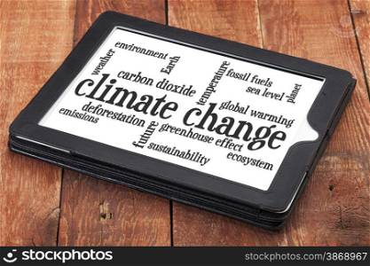 climate change word cloud on a digital tablet against rustic barn wood