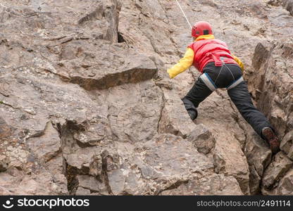 Climber adult woman climbing a rock. The winter season. Bottom view. rock climber on the mount