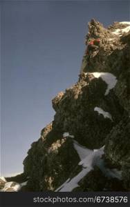 Climber nearing summit of volcanic spire, Canadian Rockies, winter Alberta, Canada