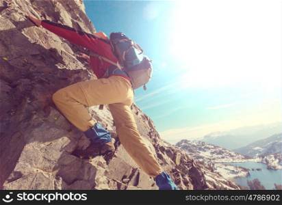 Climber scrambling up by rocky terrain