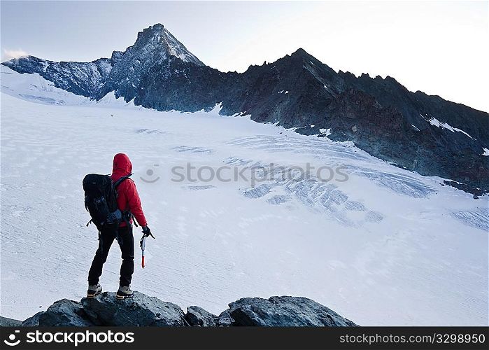 Climber stands in front the glacier and the peak of Mt Grivola, Gran Paradiso National Park, Italy