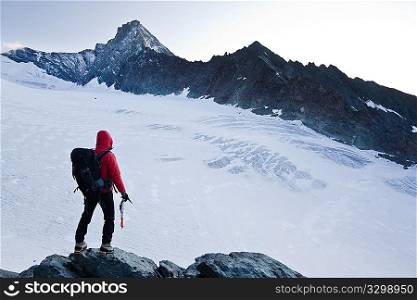 Climber stands in front the glacier and the peak of Mt Grivola, Gran Paradiso National Park, Italy