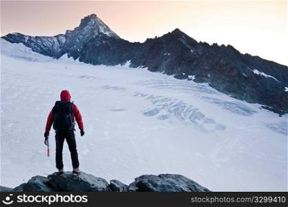 Climber stands in front the glacier and the peak of Mt Grivola, Gran Paradiso National Park, Italy.