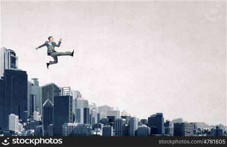 Climbing up to top . Young businessman walking on buildings roofs representing success concept