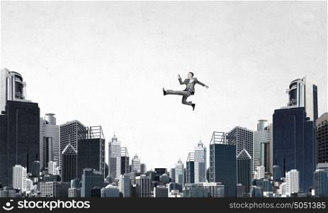 Climbing up to top . Young businessman walking on buildings roofs representing success concept