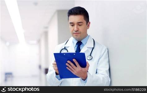 clinic, people, health care and medicine concept - doctor with clipboard at hospital corridor. doctor with clipboard at hospital corridor