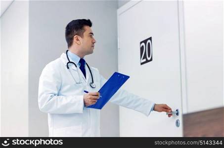 clinic, people, health care and medicine concept - doctor with clipboard opening hospital ward door. doctor with clipboard opening hospital ward door