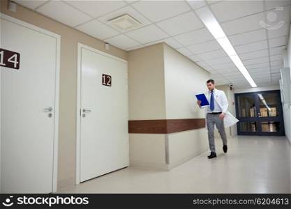 clinic, people, health care and medicine concept - doctor with clipboard walking along hospital corridor