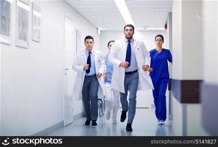 clinic, people, health care and medicine concept - group of medics runing along hospital. group of medics walking along hospital