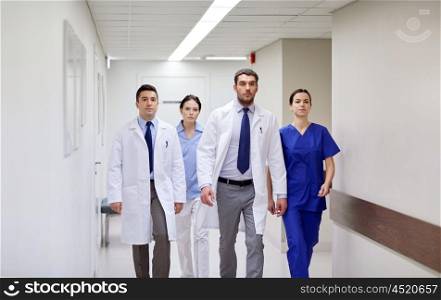 clinic, people, health care and medicine concept - group of medics walking along hospital