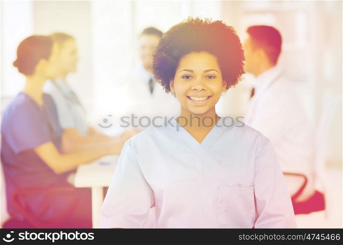 clinic, profession, people and medicine concept - happy female doctor or nurse over group of medics meeting at hospital
