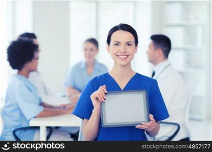 clinic, profession, people and medicine concept - happy female doctor or nurse showing tablet pc computer blank screen over group of medics meeting at hospital