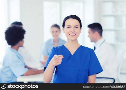 clinic, profession, people and medicine concept - happy female doctor or nurse over group of medics meeting at hospital pointing finger to you. happy doctor over group of medics at hospital