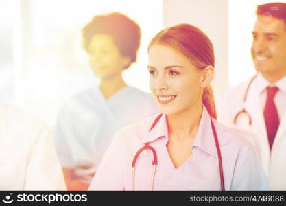 clinic, profession, people and medicine concept - happy female doctor over group of medics meeting at hospital