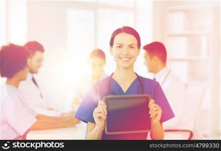 clinic, profession, people and medicine concept - happy female doctor showing tablet pc computer blank screen over group of medics meeting at hospital