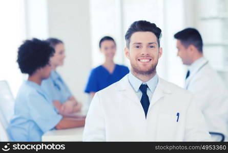 clinic, profession, people and medicine concept - happy male doctor over group of medics meeting at hospital. happy doctor over group of medics at hospital