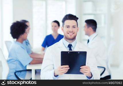 clinic, profession, people and medicine concept - happy male doctor with tablet pc computer over group of medics meeting at hospital. happy doctor with tablet pc over team at clinic