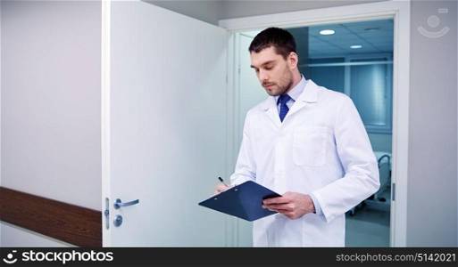 clinic, profession, people, health care and medicine concept - doctor with clipboard at hospital corridor. doctor with clipboard at hospital