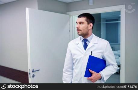 clinic, profession, people, health care and medicine concept - doctor with clipboard at hospital corridor. doctor with clipboard at hospital corridor