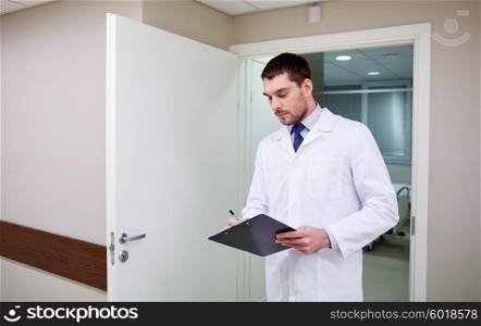 clinic, profession, people, health care and medicine concept - doctor with clipboard at hospital corridor