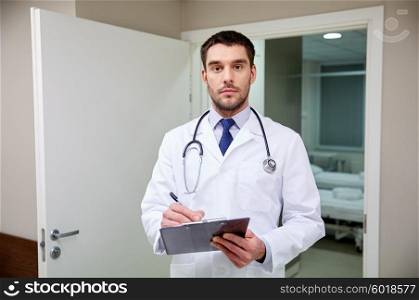 clinic, profession, people, health care and medicine concept - doctor with stethoscope and clipboard at hospital corridor