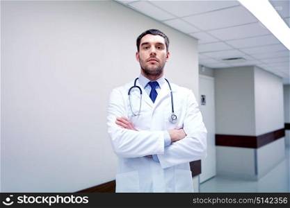 clinic, profession, people, health care and medicine concept - doctor with stethoscope at hospital corridor. doctor with stethoscope at hospital corridor