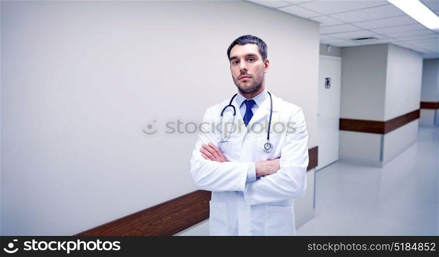clinic, profession, people, health care and medicine concept - doctor with stethoscope at hospital corridor. doctor with stethoscope at hospital corridor