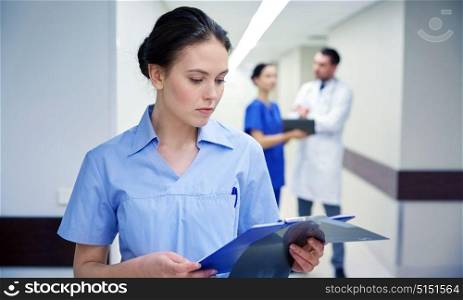 clinic, profession, people, health care and medicine concept - female doctor or nurse with clipboard at hospital. female doctor or nurse with clipboard at hospital