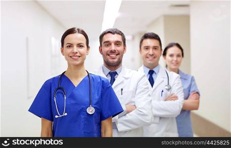 clinic, profession, people, health care and medicine concept - group of happy medics or doctors at hospital corridor