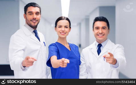 clinic, profession, people, health care and medicine concept - group of happy medics or doctors pointing finger on you at hospital corridor. group of medics pointing finger on you at hospital