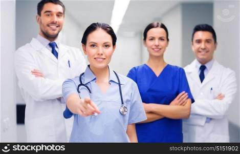 clinic, profession, people, health care and medicine concept - group of happy medics or doctors pointing finger on you at hospital corridor. group of medics pointing finger on you at hospital