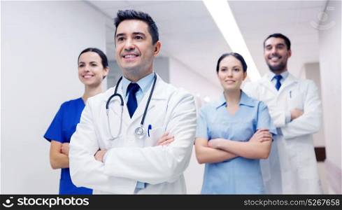 clinic, profession, people, health care and medicine concept - group of happy medics or doctors at hospital corridor. group of happy medics or doctors at hospital