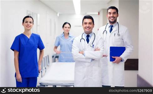 clinic, profession, people, health care and medicine concept - group of happy medics or doctors with gurney at hospital corridor. group of happy doctors with gurney at hospital