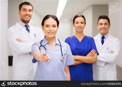 clinic, profession, people, health care and medicine concept - group of happy medics or doctors pointing finger on you at hospital corridor