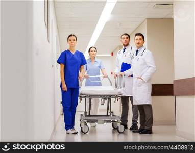 clinic, profession, people, health care and medicine concept - group of medics or doctors with gurney at hospital corridor