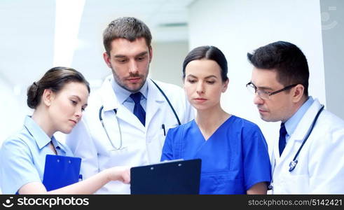 clinic, profession, people, health care and medicine concept - group of medics or doctors with clipboard at hospital corridor. group of medics at hospital with clipboard