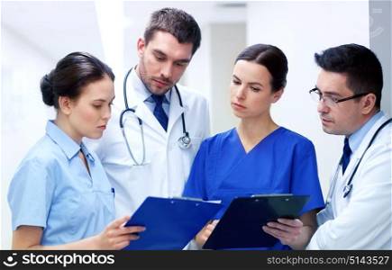 clinic, profession, people, health care and medicine concept - group of medics or doctors with clipboard at hospital corridor. group of medics at hospital with clipboard