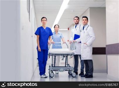clinic, profession, people, health care and medicine concept - group of medics or doctors with gurney at hospital corridor. group of doctors with gurney at hospital