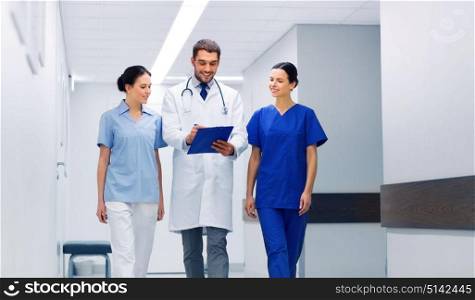 clinic, profession, people, health care and medicine concept - group of smiling medics or doctors with clipboard walking along hospital corridor. group of medics at hospital with clipboard