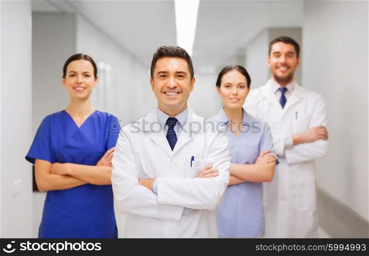 clinic, profession, people, health care and medicine concept - happy group of medics or doctors at hospital corridor
