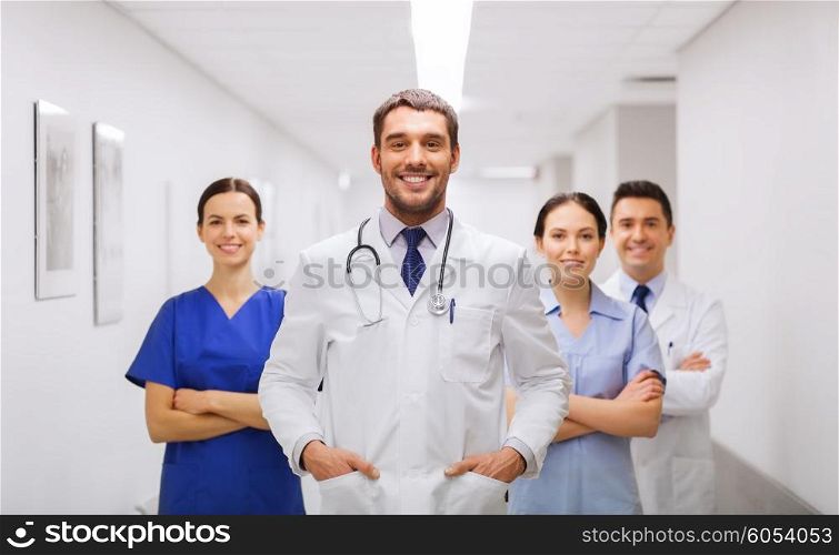 clinic, profession, people, health care and medicine concept - happy group of medics or doctors at hospital corridor