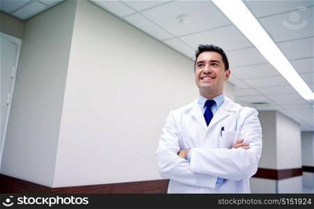 clinic, profession, people, health care and medicine concept - smiling doctor at hospital corridor. smiling doctor at hospital corridor