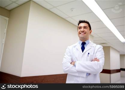 clinic, profession, people, health care and medicine concept - smiling doctor at hospital corridor