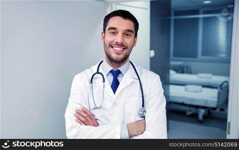 clinic, profession, people, health care and medicine concept - smiling doctor with stethoscope at hospital corridor. smiling doctor with stethoscope at hospital