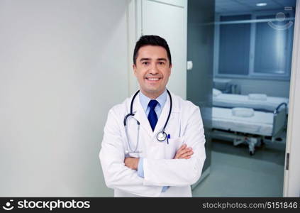 clinic, profession, people, health care and medicine concept - smiling doctor with stethoscope at hospital corridor. smiling doctor with stethoscope at hospital