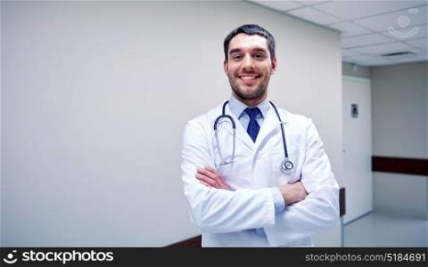 clinic, profession, people, health care and medicine concept - smiling doctor with stethoscope at hospital corridor. smiling doctor with stethoscope at hospital
